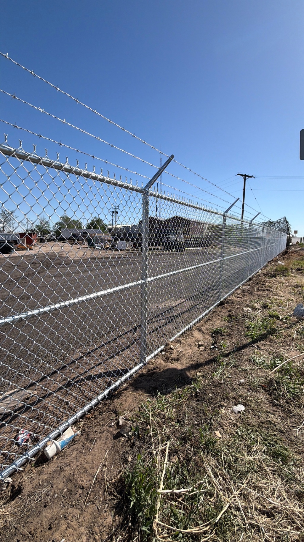 Barbed wire topped chain link fence protecting an equipment storage yard
