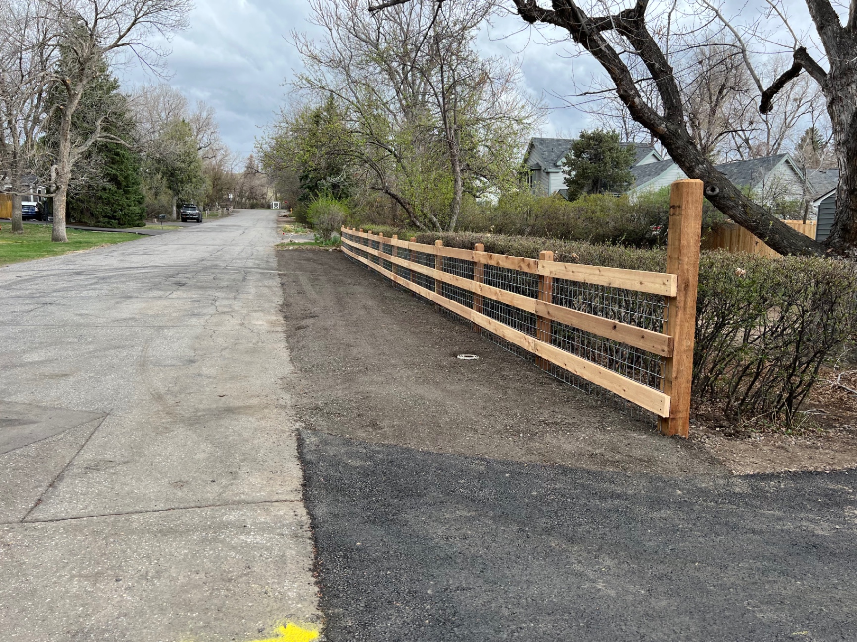 Cedar ranch rail fence with welded wire mesh along a residential lane