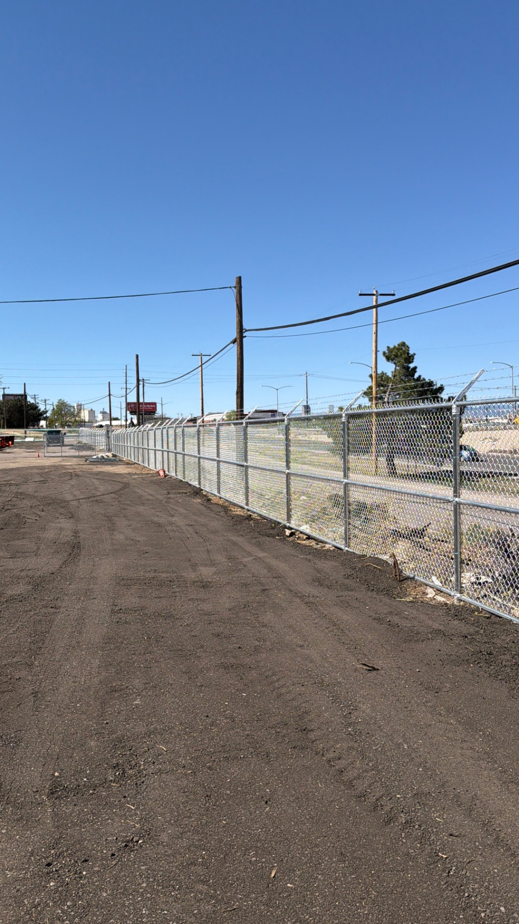 Long galvanized chain link security fence line securing an industrial lot