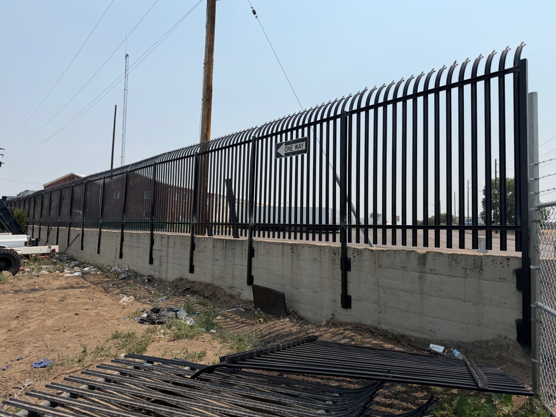 Black steel security fence mounted on a concrete retaining wall
