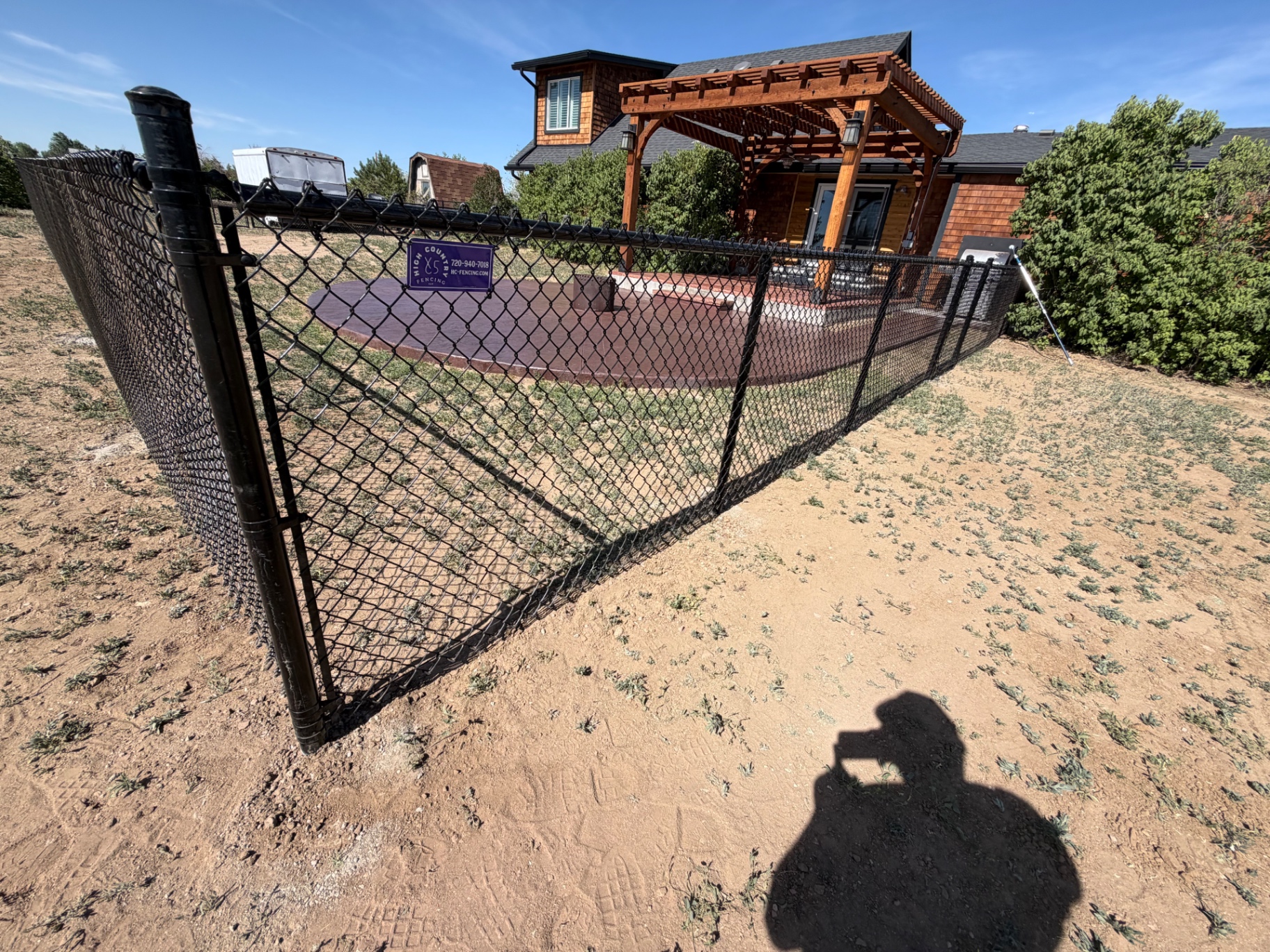 Black chain link fence enclosing a residential backyard patio